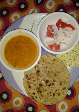A picture of Yellow dal (moong dholi) with chappati and salad.