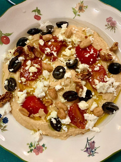 Una foto de Hummus con tomate cherry, aceitunas, frutos secos y queso feta