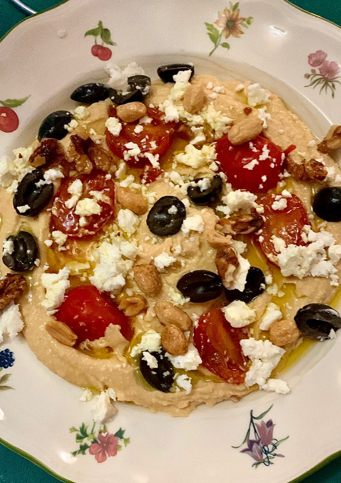 Una foto de Hummus con tomate cherry, aceitunas, frutos secos y queso feta