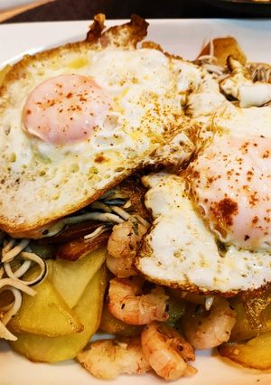Una foto de Anguriñas con gambas y huevo con base de patatas al ajo cabañil