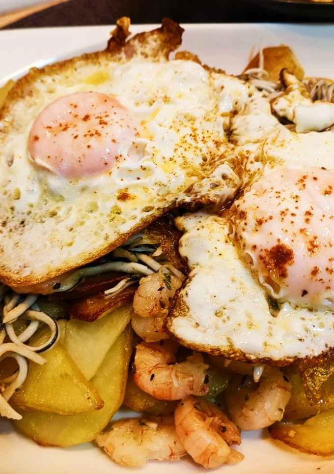 Una foto de Anguriñas con gambas y huevo con base de patatas al ajo cabañil