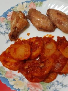 Una foto de Alitas de pollo fritas acompañadas de patatas con tomate