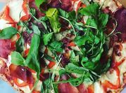 Una foto de pizza de cecina y rúcula