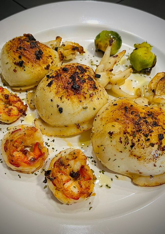 Una foto de Sepia a la plancha con gamba roja y coles de Bruselas