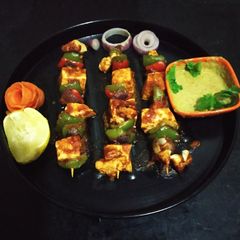 A picture of Paneer Tikka with chutney.