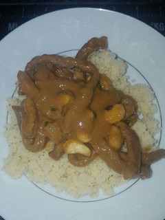 A picture of Creamy peanut sauce with beef strips and cous cous.
