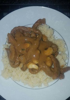 A picture of Creamy peanut sauce with beef strips and cous cous.