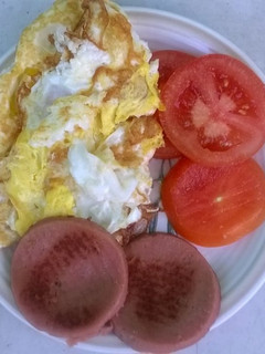 A picture of Fried eggs polony and tomato.