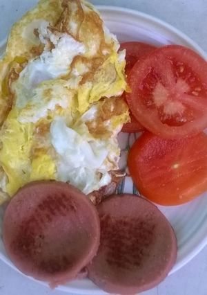 A picture of Fried eggs polony and tomato.