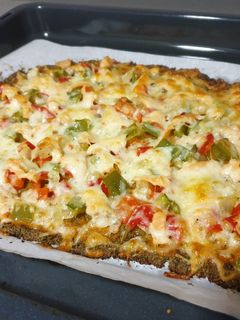 Una foto de Pizza con base de brócoli y nueces con verduras y salmón ahumado