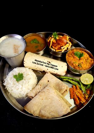 A picture of Kathiyawadi Lunch Thali (Dahi Tikhari, Sev Tameta Nu Shak, Dal Bhaat, Fulka Rotli, Chaas, Papad).
