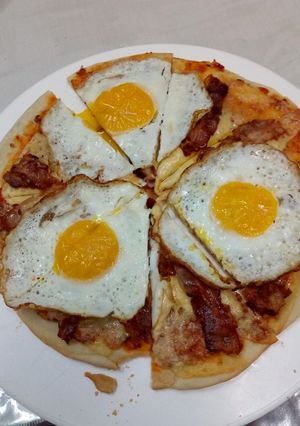 Una foto de Pizza casera de queso panceta y huevo frito