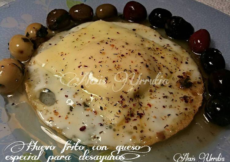 Huevo frito, con queso en lonchas y hiebas aromáticas