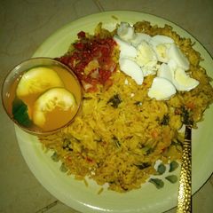 A picture of Jollof rice macaroni boiled egg en sauce and mango juice.