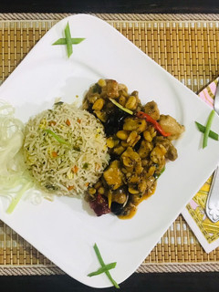 A picture of Kung pao chicken with egg fried rice.