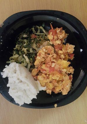 A picture of Scrambled eggs served with ugali and vegetables.