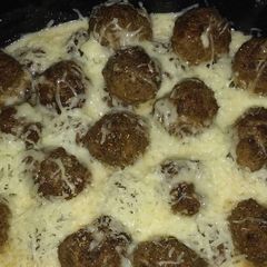 A picture of Cheesy meatballs in tomato sauce.