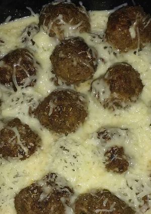 A picture of Cheesy meatballs in tomato sauce.