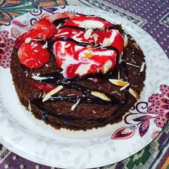 A picture of Chocolate cake with vanilla ice cream and strawberry sauce.