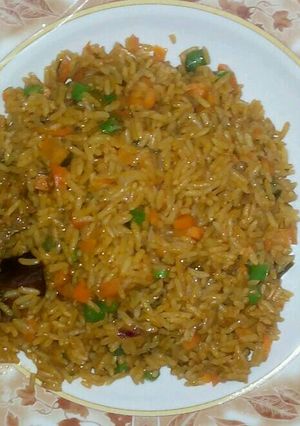 A picture of Jollof rice garnish with green pepper green peas and carriot.