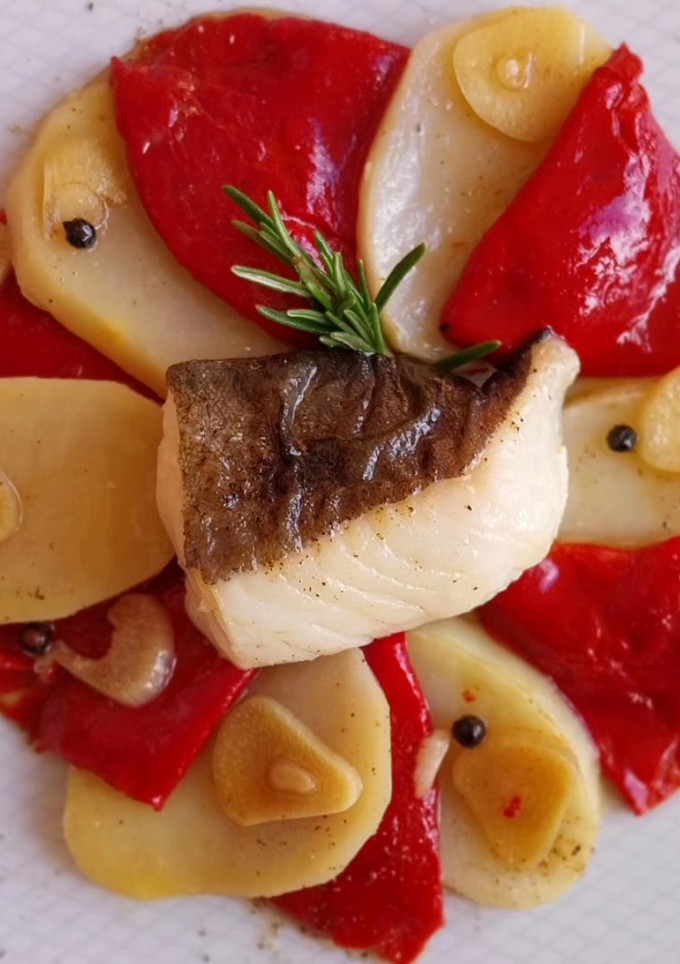 Una foto de Bacalao al romero al horno con piquillos y patatas confitadas