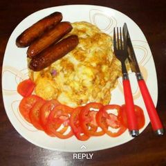 A picture of Fried eggs and sausages.. garnished with tomatoes.