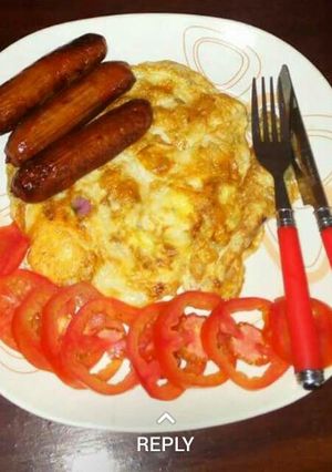 A picture of Fried eggs and sausages.. garnished with tomatoes.