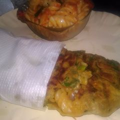A picture of Spinach kathi roll in fishbone wrap with red souce pasta.