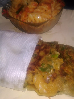 A picture of Spinach kathi roll in fishbone wrap with red souce pasta.