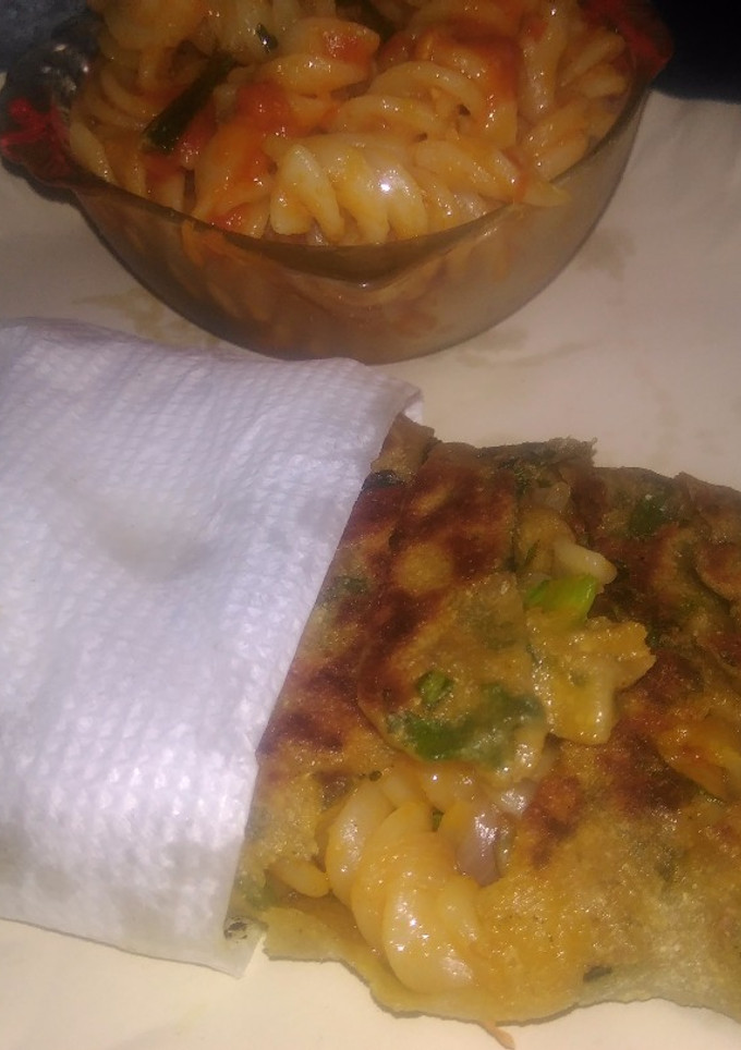 A picture of Spinach kathi roll in fishbone wrap with red souce pasta.