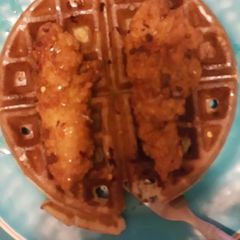 A picture of Chicken and waffles with red chili flake and honey.