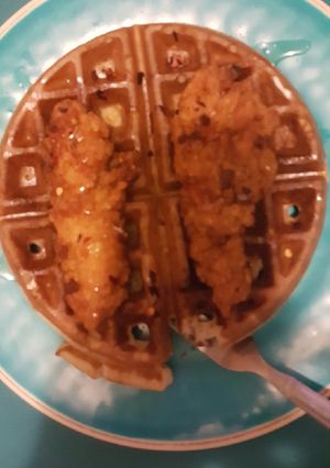A picture of Chicken and waffles with red chili flake and honey.