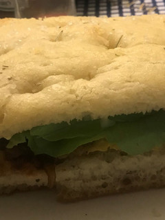 Una foto de Sándwich de filete de pollo apanado con cebolla caramelizada en pan de focaccia