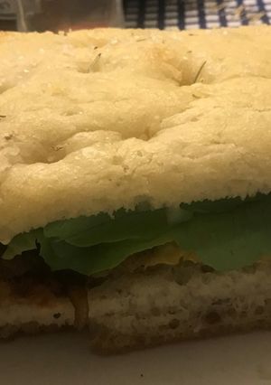 Una foto de Sándwich de filete de pollo apanado con cebolla caramelizada en pan de focaccia