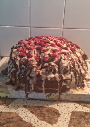 Una foto de Torta deleite con triple rellenos decorada con ganache de chocolate blanco y frambuesas