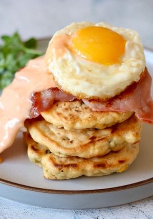 A picture of Corn cake with bacon and sriracha mayo sunny side up.