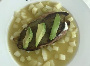 Una foto de Nopal relleno de frijoles y queso panela sobre una capa de chayote y papa en salsa verde