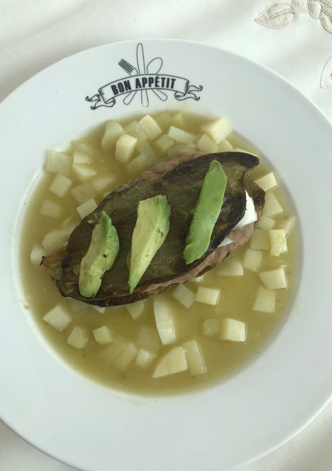 Una foto de Nopal relleno de frijoles y queso panela sobre una capa de chayote y papa en salsa verde