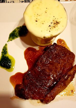 Una foto de Bife de chorizo grillado con huevo roto y espuma de papas