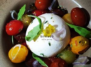 Una foto de Ensalada de burrata con tomate cherry, chalota y caviaroli