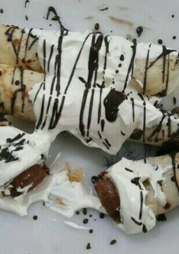 Una foto de Panqueques rellenos de dulce de leche bañado con crema y chocolate