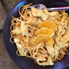 A picture of Spaghetti with chicken, curry and orange.