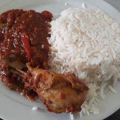 A picture of White rice with tomato stew and chicken.