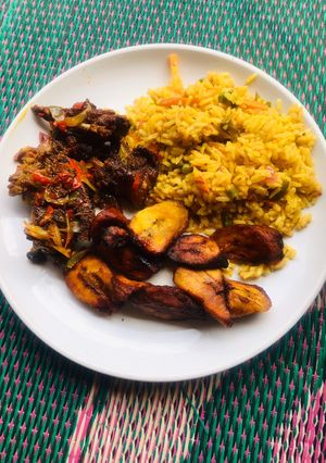 A picture of Jollof rice, fried plantain & pepper meat🥩.