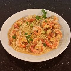 A picture of Poached Shrimp with Siriacha Cream Sauce on Angel Hair Pasta.