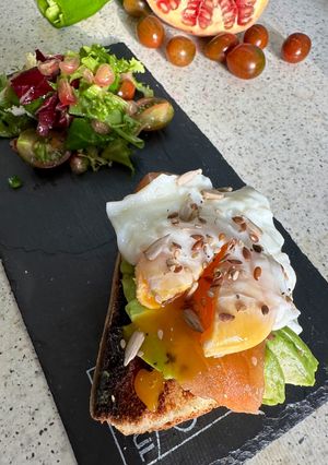 Una foto de Tosta gourmet de huevo escalfado con salmón y aguacate con ensalada de granada