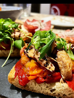 Una foto de Tosta de pimiento caramelizado, tomate confitado, melva y rúcula