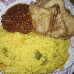 A picture of Colored rice and fried yam with egg.