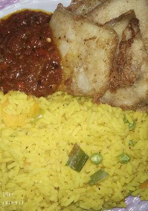 A picture of Colored rice and fried yam with egg.