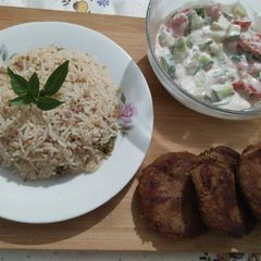 A picture of Qeemay rice with shami kabab and vegetables salad.